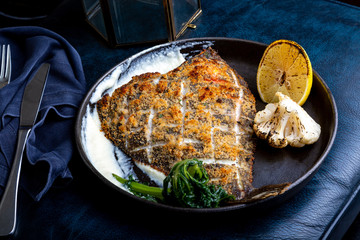 Flounder fillet roasted in a skillet with herbs and lemon