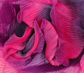 Flounces of pink fabric wound by waves. Texture and background from fabric.