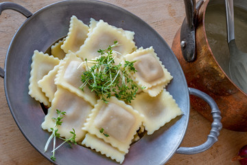 Ravioli auf Zinnteller und Kupfertopf