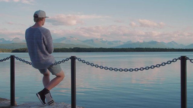 Person sittning in front of fantastic scenery in with ocean and mountains in Molde Norway during summer sunset