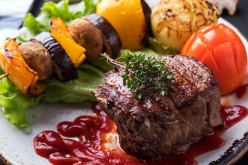 Juicy medium beef steak  with red sauce and grilled vegetables
