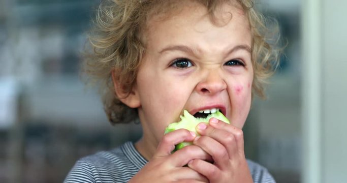 Infant eating green apple fruit, taking a bite