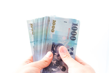 A hand holding a 1000 New Taiwan Dollar bill.
