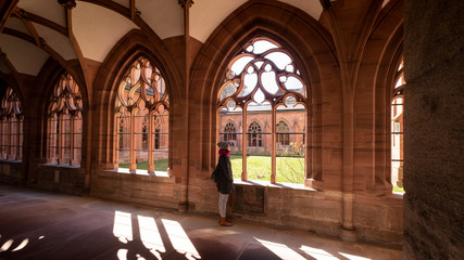 Fototapeta premium Frau geniesst die Stille im Klostergang des Münsters in Basel