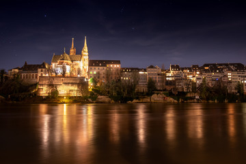 Beleuchtetes Basler Münster am Rheinufer in der Nacht