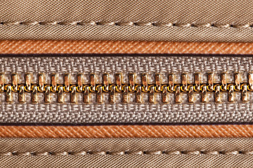 Brown handbag metal zipper closeup. Fashion fabric texture with thread sew.