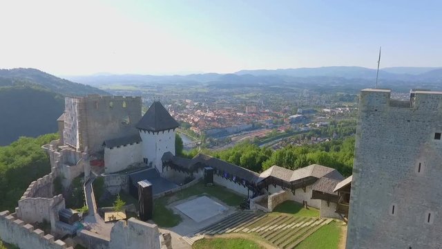 A castle is standing on a hill overlooking the city of Celje. There is a courtyard in the middle and a high tower.