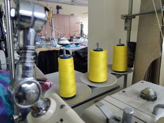 Three spools of thread tucked into a sewing machine on the background of a sewing workshop