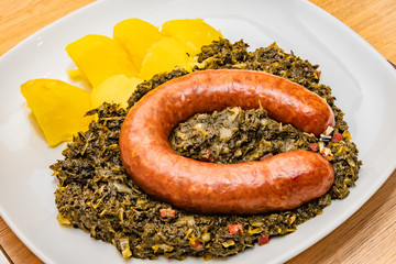 Norddeutsches Gericht Grünkohl Braunkohl mit Bregenwurst auf weißen Teller