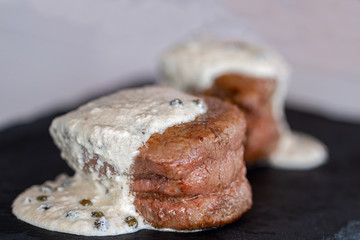 Two tall slices of tenderloin with green pepper sauce.