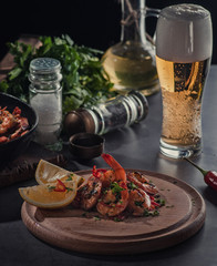 boiled shrimp with lemon and beer on a dark plate