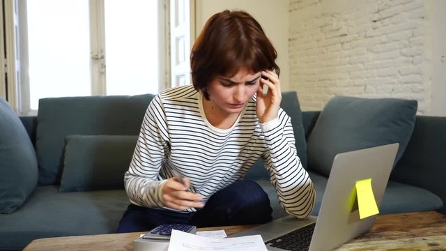 4K video. Worried and desperate woman feeling stressed paying credit card debts and bills on laptop computer on sofa at home. In business and home finances and financial problems concept.