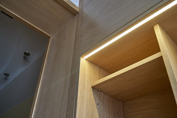 Wooden cupboard with drawers, empty shelves and LED lights. Modern furniture