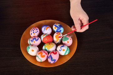 girl paints Easter eggs. hand, brush and paint on the table. preparation for Easter.