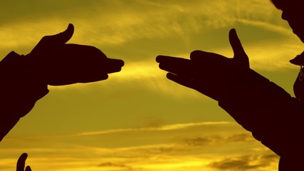 Children make shape of dog shape with hands at sunset. girls hold the gesture of a dog symbol with their fingers against sky. children show with hands the silhouette of an animal. shadow play