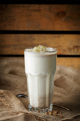 sprouted grain milkshake in the glass, on wooden board backdrop