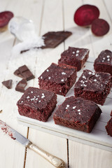 Beetroot brownie on a white wooden background from a side, longer knife
