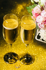 Bouquet with beautiful roses and glasses of champagne on black background with gold 