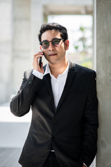 Handsome Asian businessman using smart phone outdoor.