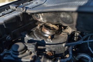 Rusted top spring suspension located in the engine compartment.