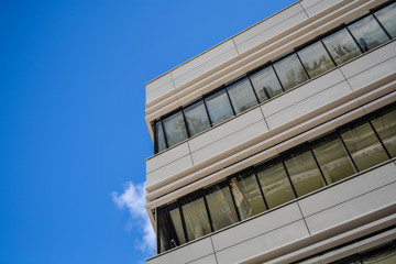 Modern buildings of unusual forms from glass and metal. Geometry of lines and curves. The inclined facade. Blue sky.