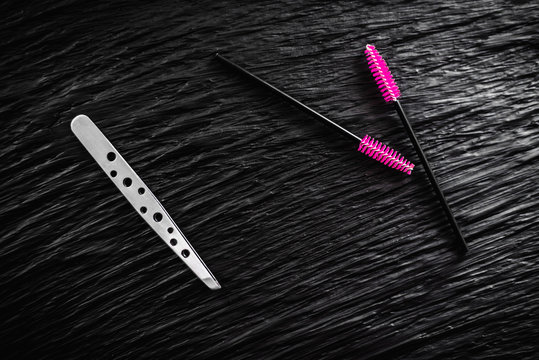 on the black background lies a pair of tweezers and eyebrow comb brush the top view copy space