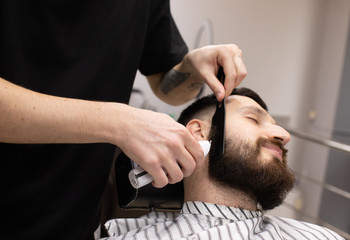 Fototapeta premium Client during beard shaving in barber shop 