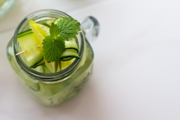 refreshing water with mint, lime and cucumber close-up on a white background and space for text.