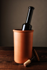 Terra cotta wine chiller on a rustic wood table.