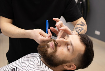 Fototapeta premium Client during beard shaving in barber shop 