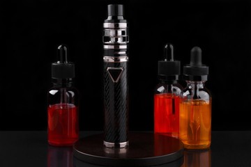 Electronic cigarette and vape liquids on black background