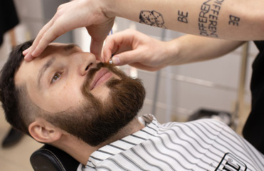 Shaving process of beards in Barbershop. Master makes a haircut beard client with vintage straight razor. 