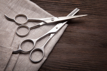 Hairdressing scissors on a black wood background.