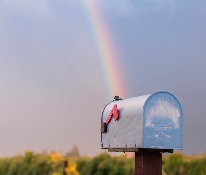 Rainbow falling from sky into mailbox on rainy day