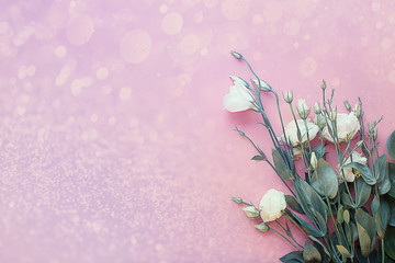 bouquet of white eustomas on a light pink vintage background with with highlights and bokeh