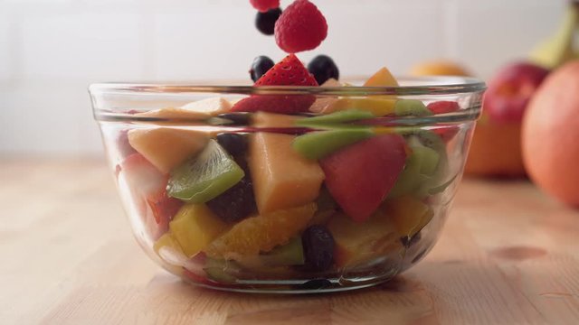 Camera follows putting fresh fruit into fruit salad. Shot with high speed camera, phantom flex 4K. Slow Motion.