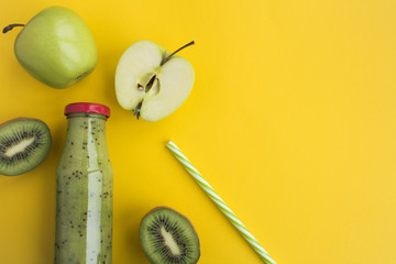 Smoothies with kiwi and green apples in the glass bottle on the yellow  background.Top view.Copy...