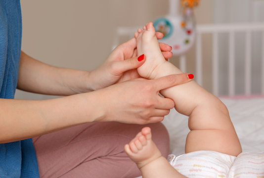 Closeup of mother parent doing heel toe foot massage and physical exercises to newborn baby son daughter. Early development and health care lifestyle concept