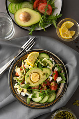 Healthy salad of fresh vegetables - tomatoes, avocado, arugula, egg, spinach. Flat lay. Top view.