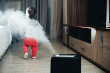 a little girl in red pants looks and touches the humidifier. Moisture in the house concept