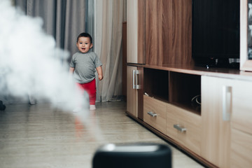 a little girl in red pants looks and touches the humidifier. Moisture in the house concept