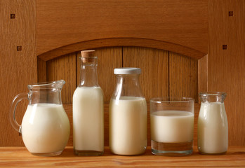 fresh milk in glass containers with oak wooden background