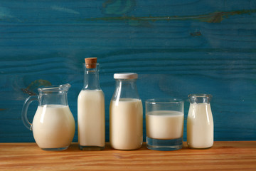 fresh milk in glass containers with blue wooden background - closeup