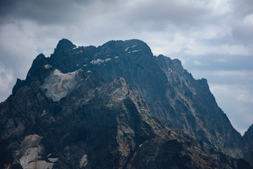 Obraz premium The peaks of the Caucasus Mountains in cloudy clouds and the rays of the sun through them in the outskirts of Dombai. And on the tops of snow lies.