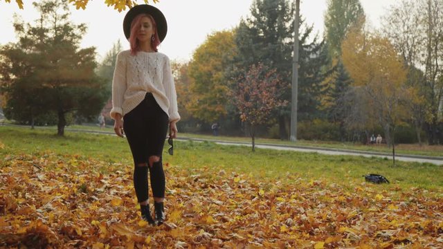 Attractive girl walks among autumn crimson maple leaves at park