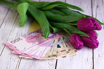 Bouquet of purple tulips and  Ukrainian national currency (hryvnia), money - a gift for the holiday, concept