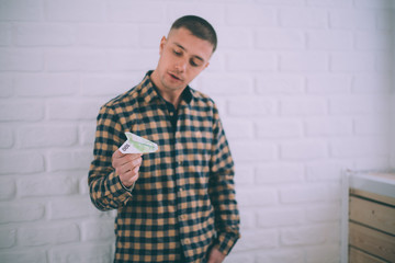 a man with a Euro bill in the form of an airplane against a brick wall