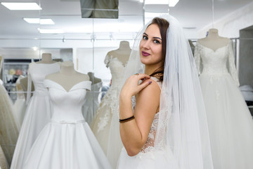 Young woman in wedding dress and veil in bridal shop