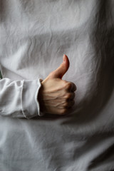 Woman hand with thumb up on a gray background.