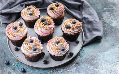 Delicious cupcakes with blueberry cream, fresh blueberries and nut sprinkel.